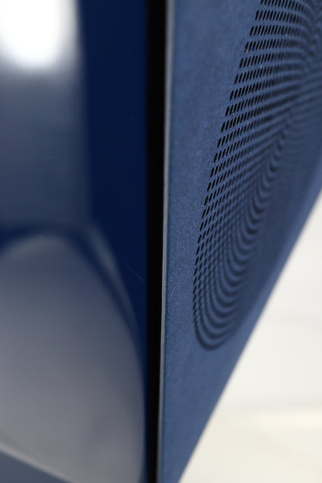 Close up of a used KEF R3 META Standmount Speaker W/ Stand in an indigo gloss finish showing scratch on front left corner