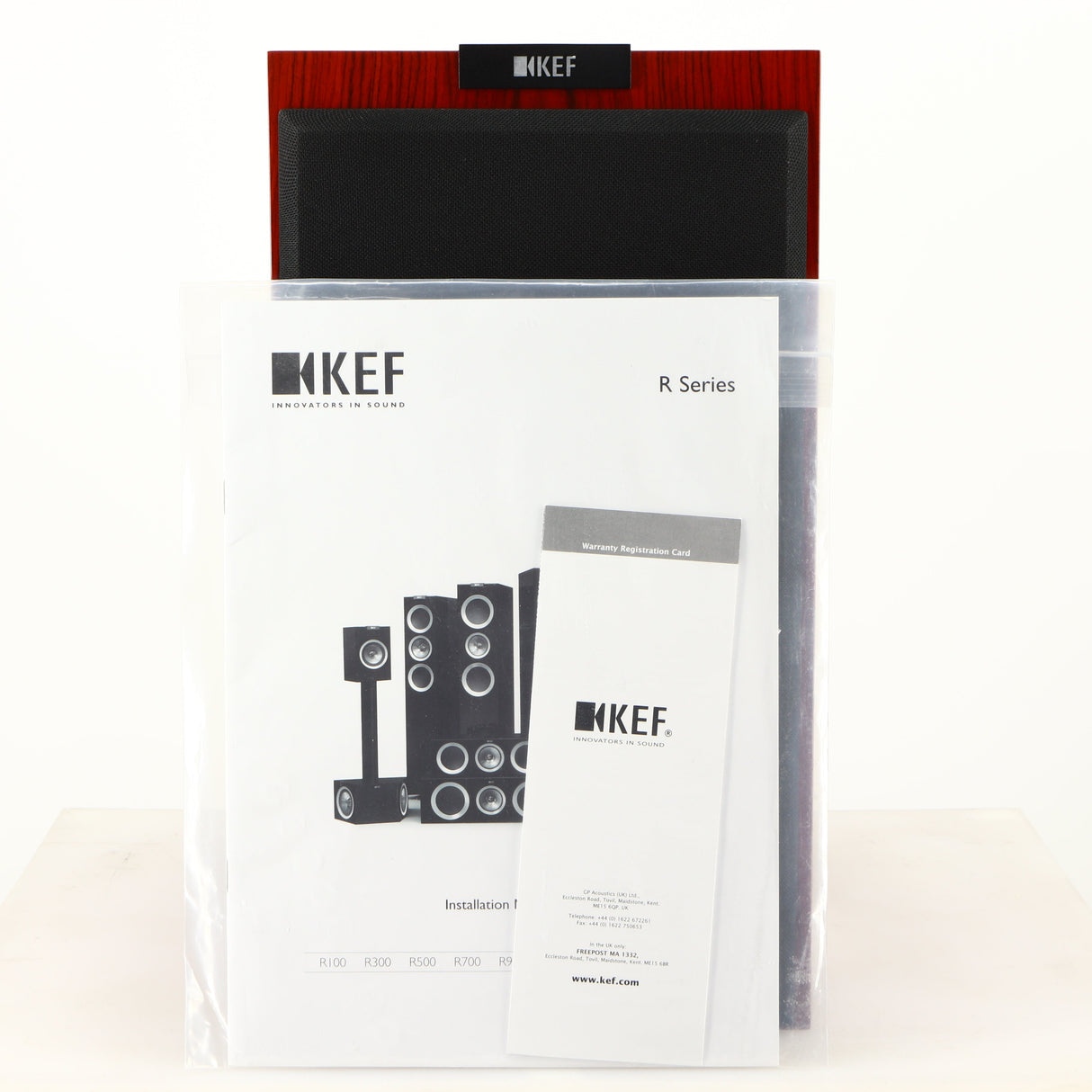 Front view of a used KEF R300 Standmount Speaker in a rosewood finish showing Manual and Warranty Registration Card