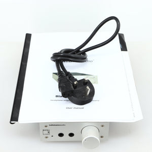 top of a used Lehmann Black Cube Linear Headphone Amplifier in a silver finish showing Mains Cable and Manual