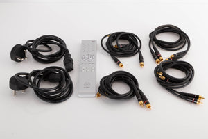 Accessories of a Linn Majik DSM/1 Network Player and Majik 6100 Power Amplifier showing 2x Mains cables, Remote, and 4x RCA Cables 