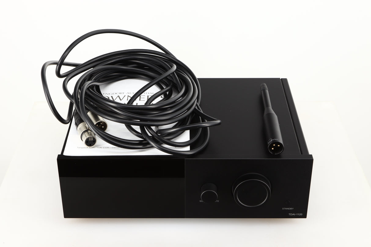 Top of a used Lyngdorf TDAI-1120 Integrated Streaming System in a black finish showing Manual, Set-Up Mic and XLR Cable