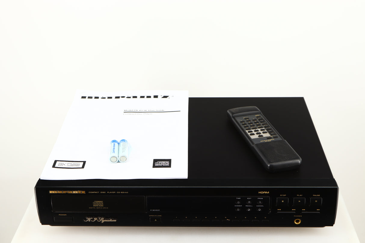 Top of a used Marantz CD63 KI Signature CD Player in a black finish showing 2x Batteries, Manual and Remote
