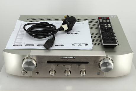 Accessories of a used Marantz PM6005 Integrated Amplifier in silver finish showing manual, mains cable, and remote