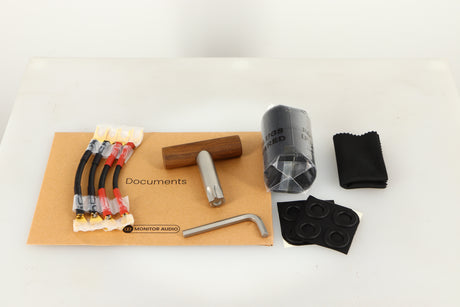 Accessories for used Monitor Audio Platinum PL100 III Standmount Speakers in a piano black finish showing Documents, 4x Links, Bung, Cloth, 4x Feet and Allen Key