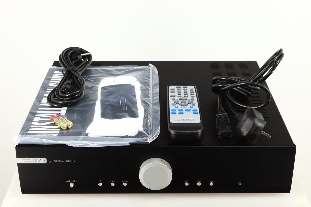 Top of a used Musical Fidelity M2si Integrated Amplifier in a black finish showing Mains Cable, Remote, Manual, Gloves, Cleaning Cloth, 2x Batteries and Schuko Cable