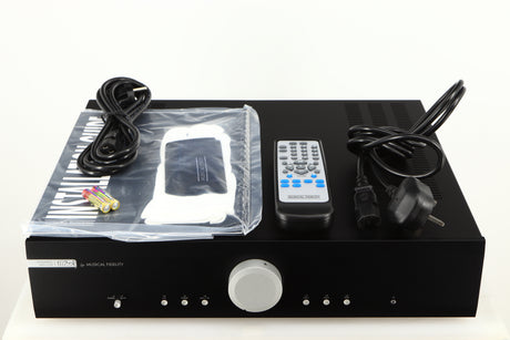 Top of a used Musical Fidelity M2si Integrated Amplifier in a black finish showing Mains Cable, Remote, Manual, Gloves, Cleaning Cloth, 2x Batteries and Schuko Cable