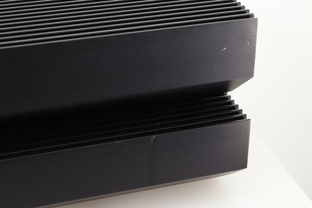 Close up view of a pair of used Musical Fidelity MA50 Class A Monoblock Power Amplifiers in Black finish showing scratches on the right side of the fascia