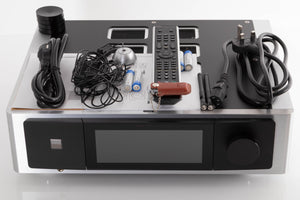 Top of a used NAD M33 V1 BluOS Streaming DAC Integrated Amplifier showing Remote, Batteries, USB Stick, Mains Cable, Schuko Cable, Manual, Microphone, Spare Feet, Wi-Fi Antenna and Bluetooth Antenna 