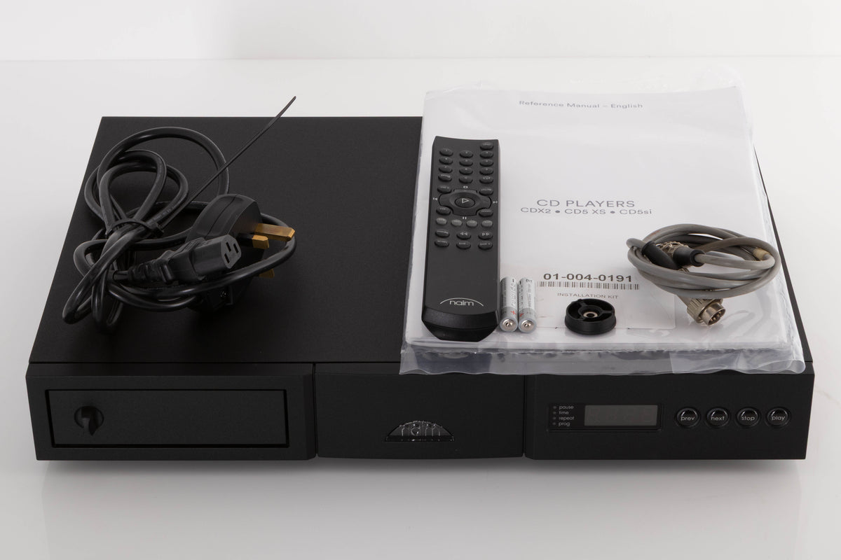 Top of a used Naim CD5si CD Player in a Black finish showing Remote, Batteries, Manual, CD Puck, Mains Cable and SNAIC5