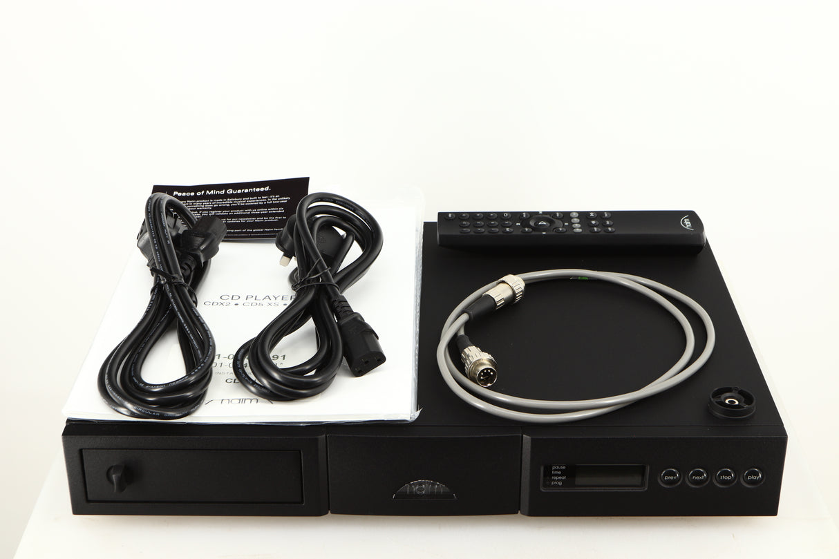 Top of a used Naim CD5si CD Player in a black finish showing Mains Cable, Schuko Cable, CD Puck, SNAIC5, Remote and Manual