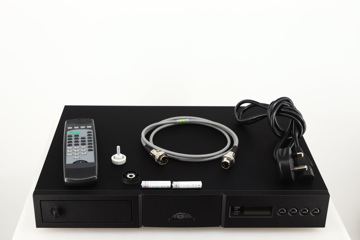 Top of a used Naim CD5X CD Player in a black finish showing Batteries, SNAIC5, Mains Cable, Remote, CD Puck and Transit Bolt