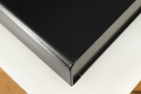Close up of a used Naim Flatcap Power Supply in a black finish showing small graze on front edge and left side