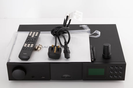 Top of a used Naim NAC N-272 Pre Amplifier in a Black finish showing Manual, Mains Cable, Remote, Batteries, Wi-Fi Antenna, Aerial Antenna, BNC Adaptor and Link Plug