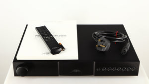Top of a used Naim Nait XS-2 Integrated Amplifier in a black finish showing Mains Cable, Remote, Manual and 2x Batteries