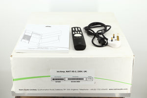 Box of a used Naim Nait XS-2 Integrated Amplifier showing mains cable, manual, and remote