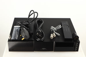 Top of a used Naim NDX2 Network Streamer in a black finish showing Manual, Remote, Batteries, Mains Cable, Schuko Cable, SNAIC5, Link Plug, BNC Adaptor, Bluetooth Antenna and Wi-Fi Antenna