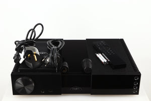 Top of a used Naim NSC222 Pre Amplifier in a black finish showing Mains Cable, Manual, Remote, Batteries, Schuko Cable and Burndy Plugs