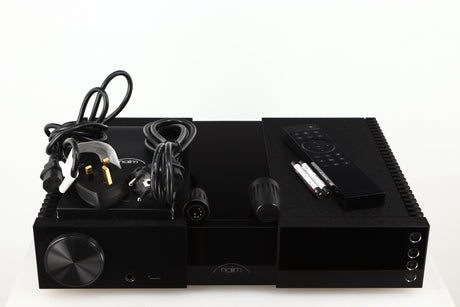 Top of a used Naim NSC222 Pre Amplifier in a black finish showing Mains Cable, Manual, Remote, Batteries, Schuko Cable and Burndy Plugs