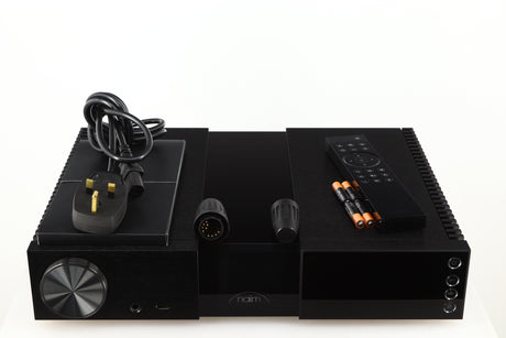 Top of a used Naim NSC222 Pre Amplifier in a black finish showing Mains Cable, Manual, Remote, Batteries and Burndy Plugs