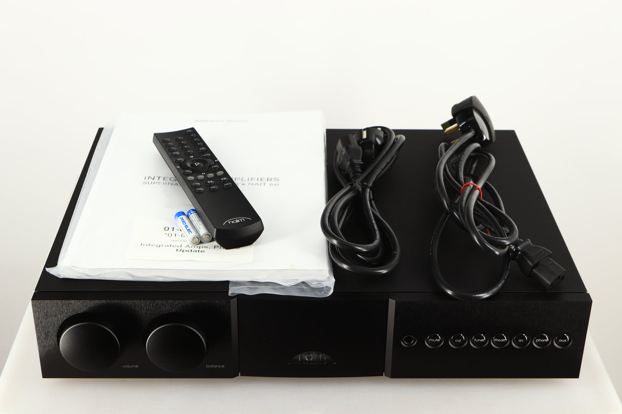 Top of a used Naim Supernait 3 Integrated Amplifier in a black finish showing Remote, 2x Batteries, Manual, Schuko Cable and Powerline Lite