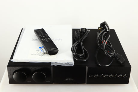 Top of a used Naim Supernait 3 Integrated Amplifier in a black finish showing Remote, 2x Batteries, Manual, Schuko Cable and Powerline Lite