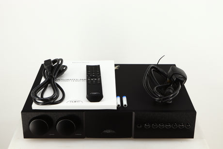 Top of a used Naim Supernait 3 Integrated Amplifier in a black finish showing Mains Cable, Remote, 2x Batteries, Schuko Cable and Manual