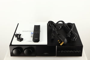 Top of a used Naim Supernait 3 Integrated Amplifier in a black finish showing Manual, Remote, Batteries, Mains Cable, Schuko Cable and Link Plugs
