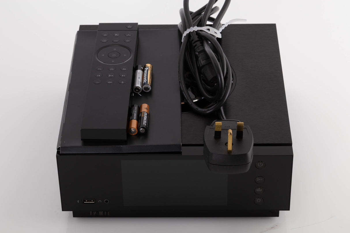Top of a used Naim Uniti Atom Integrated System in a Black finish showing Remote, Batteries, Manual and Mains Cable