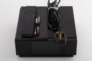 Top of a used Naim Uniti Atom Integrated System in a Black finish showing Remote, Batteries, Manual and Mains Cable