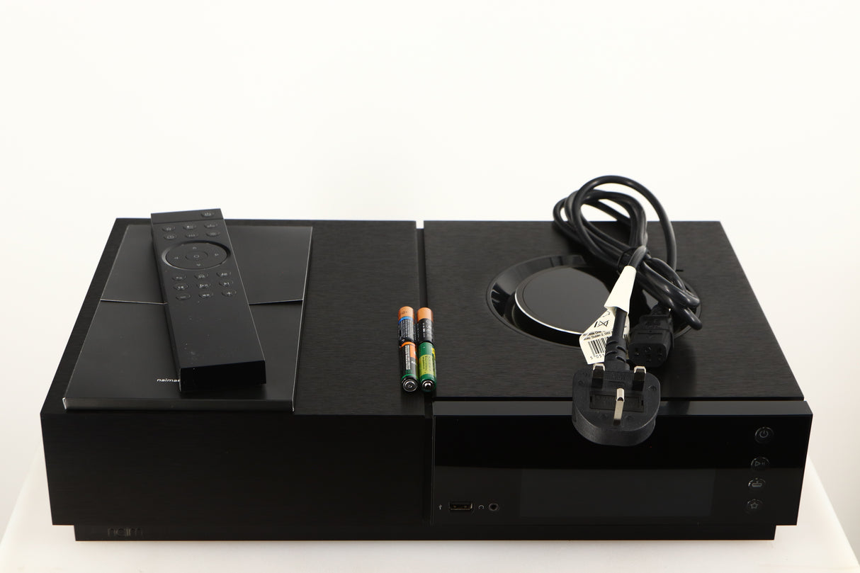 Top of a used Naim Uniti Nova Integrated System in a black finish showing Remote, Mains Cable, 4x Batteries and Manual