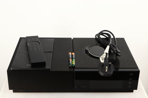 Top of a used Naim Uniti Nova Integrated System in a black finish showing Remote, Mains Cable, 4x Batteries and Manual