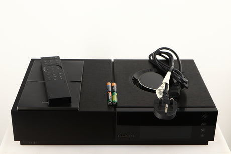 Top of a used Naim Uniti Nova Integrated System in a black finish showing Remote, Mains Cable, 4x Batteries and Manual