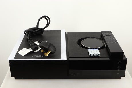 Top of a used Naim Uniti Star Integrated Music System in a black finish showing Manual, Mains Cable, Batteries and Remote