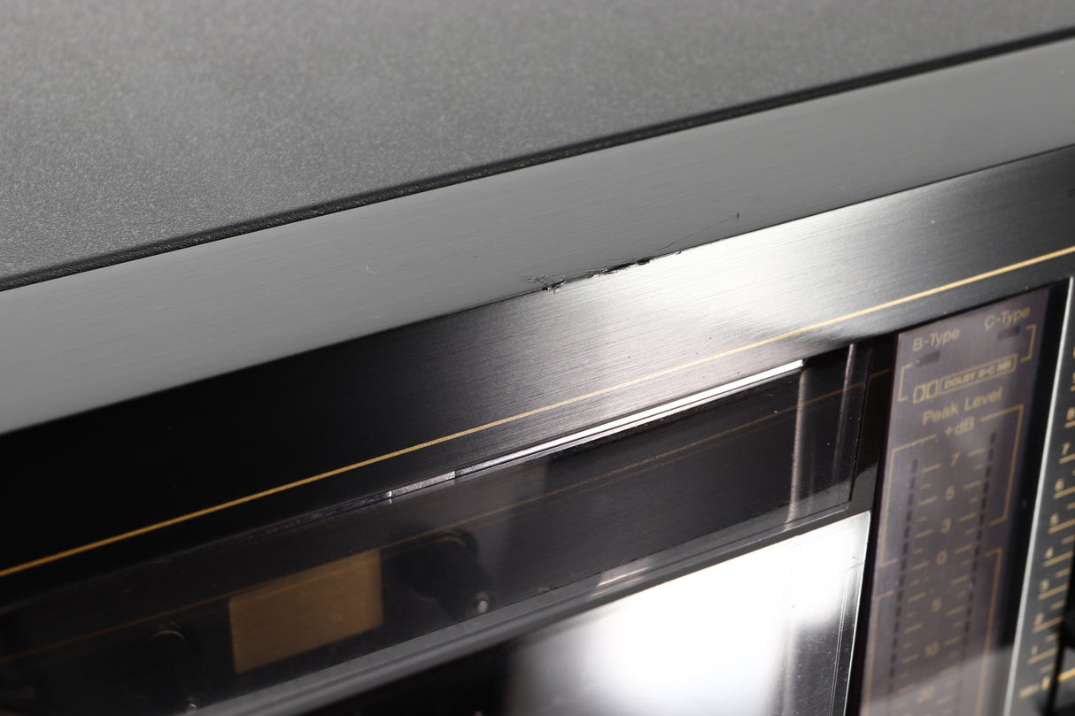 Close up view of a used Nakamichi RX-202E Cassette Deck showing damage to the front edge