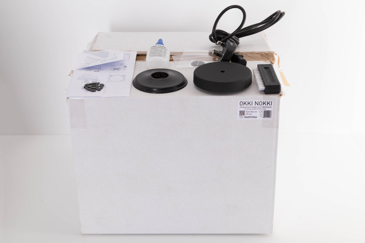Box for a used Okki Nokki One Record Cleaning Machine in a Black finish showing Manual, Mains Cable, Cleaning Fluid, Brush and Spare Logo