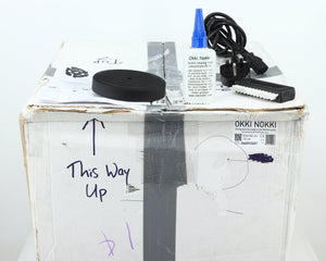 Box for a used Okki Nokki One Record Cleaning Machine in a black finish showing Manual, Cleaning Fluid, Brush and Mains Cable  