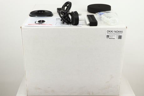 Box for a used Okki Nokki One Record Cleaning Machine in a black finish showing Mains Cable, Logo, Brush, Cleaning Fluid and Manual