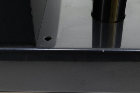 Close up view of a used PrimaLuna Prologue Premium Pre Amplifier in Black finish showing a small chip on the left side and that the back left rubber washer is missing