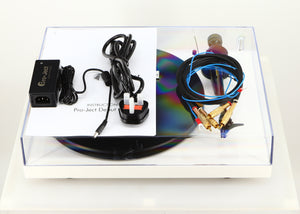 Top of a used Project Debut Carbon Turntable / Ortofon 2M Blue Cartridge in a white finish showing Project High Power It, Manual and Interconnect Cable