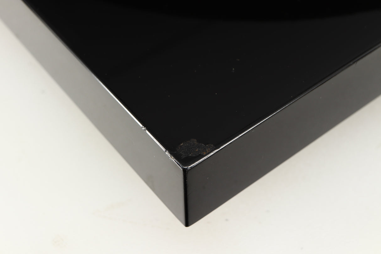 Close up of a used Project Debut Carbon Turntable in a piano black finish showing chip on front left corner