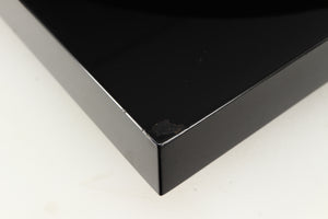 Close up of a used Project Debut Carbon Turntable in a piano black finish showing chip on front left corner