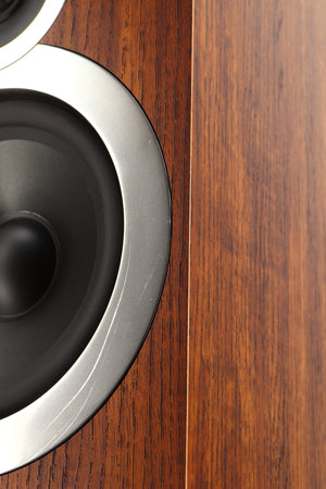Close up of a used Q Acoustics 3050i Floorstanding Speakers in a walnut finish showing scratching on bass driver surround