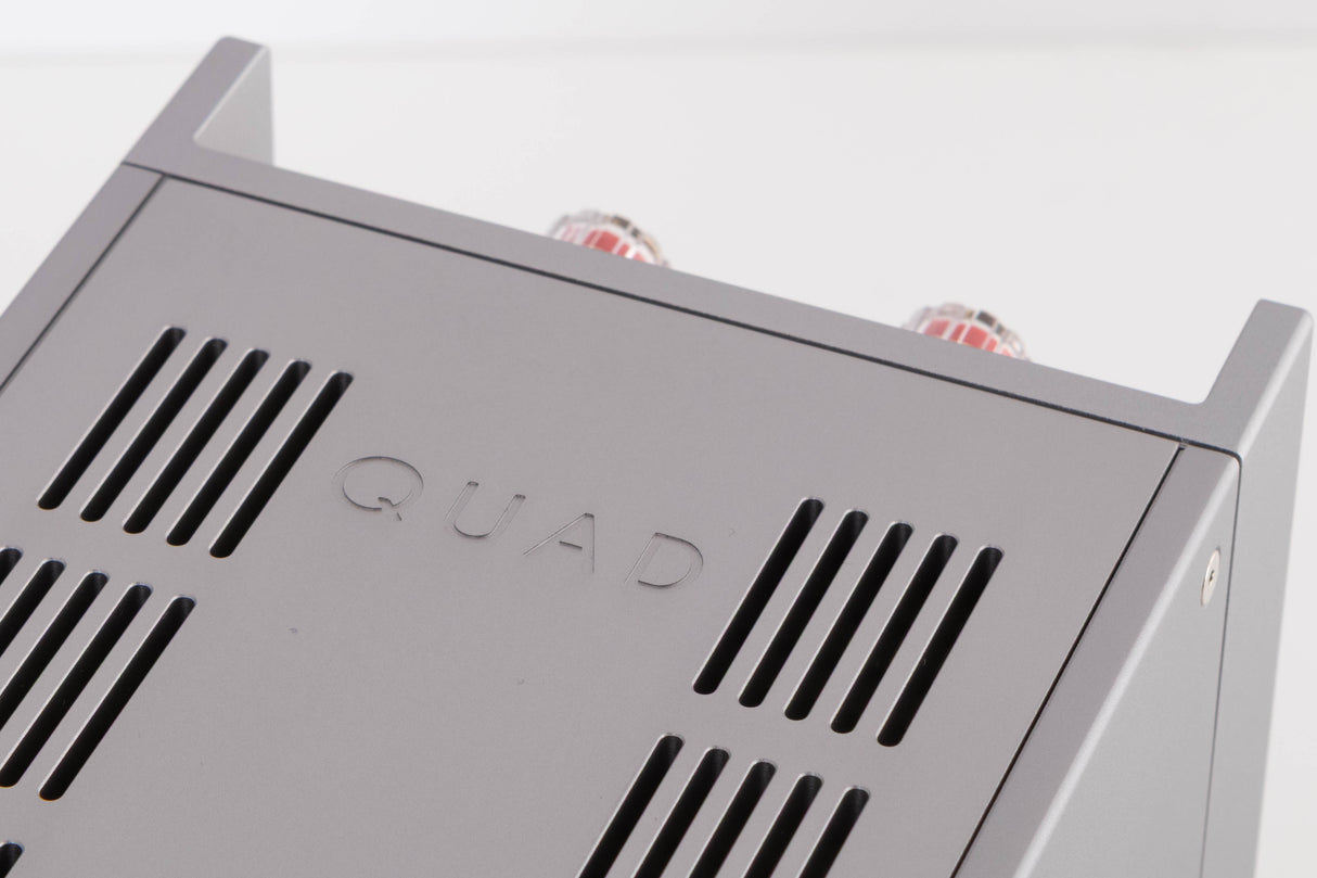 Close up of a used Quad 303 Power Amplifier in a Silver finish showing logo on top