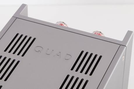 Close up of a used Quad 303 Power Amplifier in a Silver finish showing logo on top