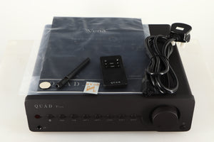 Top of a used Quad Vena Integrated Amplifier in a lancaster grey finish showing Remote, Battery, Mains Cable, Antenna and Manual