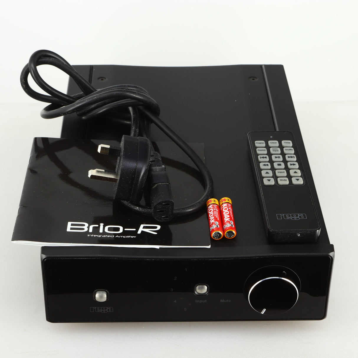 Top view of a used Rega Brio-R Integrated Amplifier in a black finish showing manual, mains cable, remote and 2x batteries