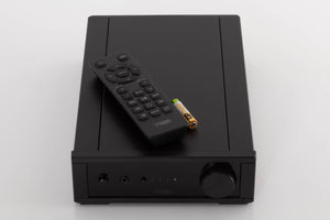 Top of a used Rega IO Integrated Amplifier in a Black finish showing Remote and Batteries