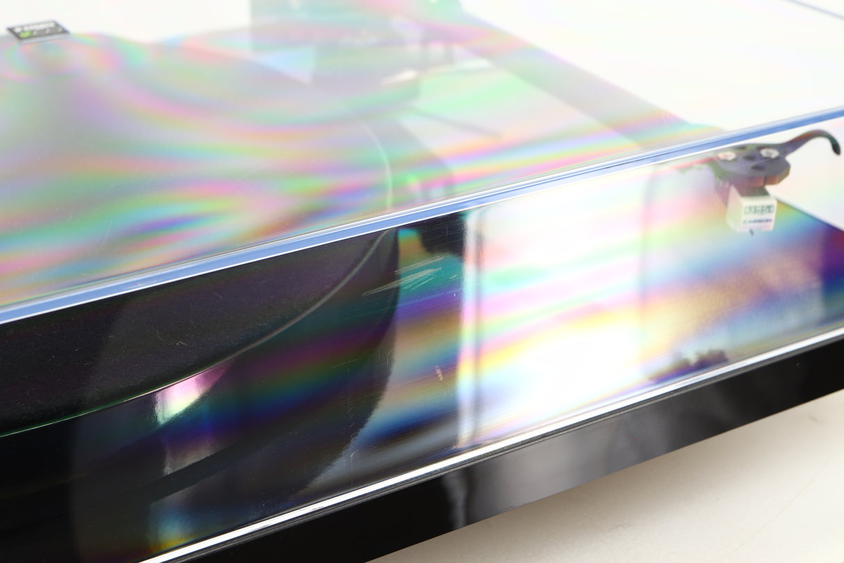 Close up view of a used Rega Planar 1 ECO Turntable in Black Gloss finish showing some scratching on the lid on the front side