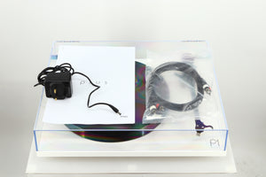 Top view of a used Rega Planar 1 Plus Turntable in a white finish showing a manual, power supply and an interconnect cable