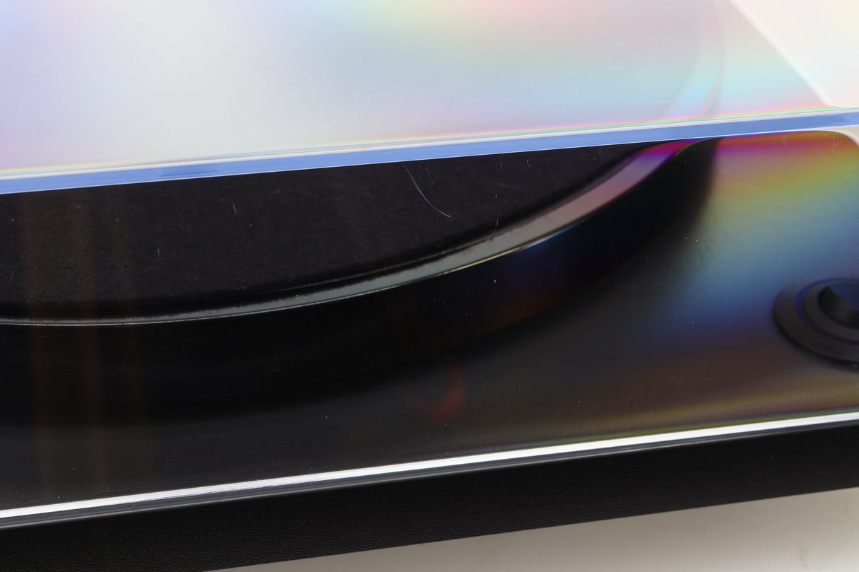 Close up of a used Rega RP1 Turntable in a cool grey finish showing a scratch on the left side of the lid